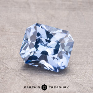A square-cut 1.86-carat Ceylon Sapphire is showcased on a textured surface, with the "Earth's Treasury" logo visible at the bottom.