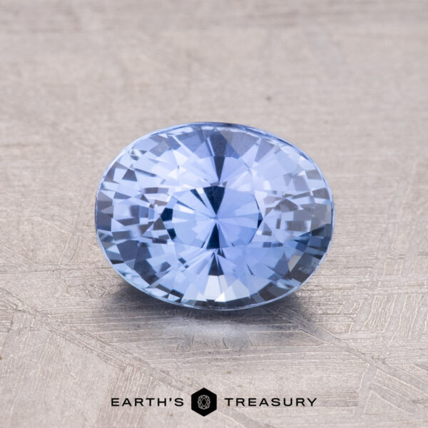 1.54-Carat Ceylon Sapphire A 1.54-carat Ceylon Sapphire, featuring a round, faceted blue design, is set on a textured surface with the "Earth's Treasury" logo at the bottom.