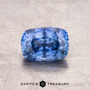The 1.35-Carat Ceylon Sapphire, cushion-cut and displayed on a textured surface, with "Earth's Treasury" below.
