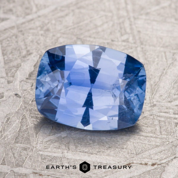 A 2.26-carat Sky Blue Ceylon Sapphire in a cushion cut is displayed on a textured surface with a watermark reading "Earth's Treasury.