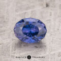 A 1.53-carat purple Ceylon sapphire is showcased on a textured gray surface, exhibiting brilliant reflections.