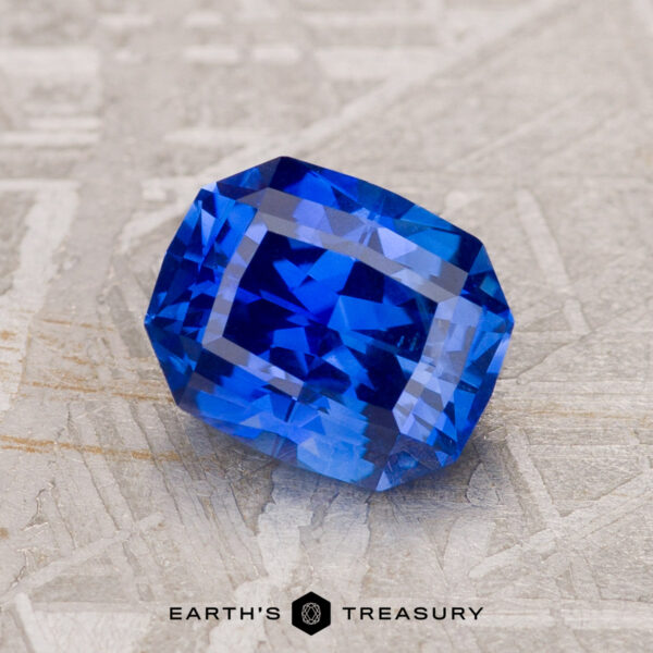 1.93-Carat Royal Blue Ceylon Sapphire A 1.93-Carat Royal Blue Ceylon Sapphire with a rectangular shape and multiple facets rests on a textured surface.