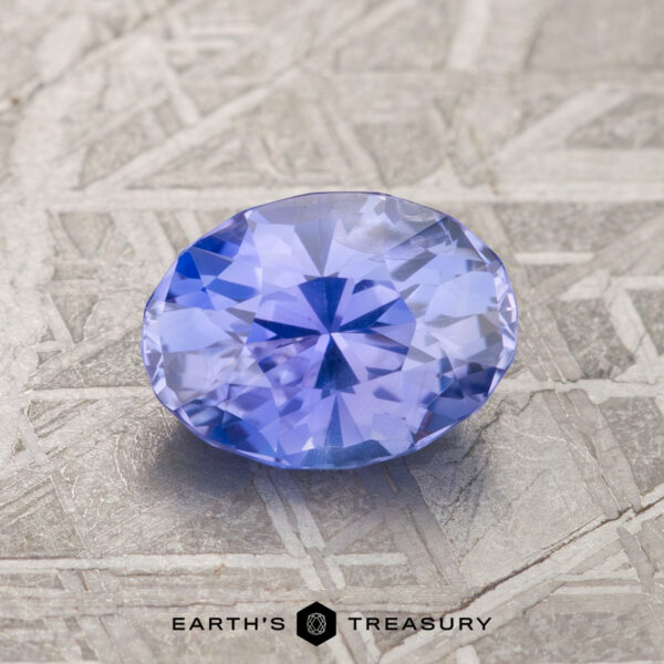 1.66-Carat Violet Blue-Purple Color Change Ceylon Sapphire A 1.66-carat violet blue-purple color change Ceylon sapphire rests on a textured surface with the "Earth's Treasury" logo underneath.