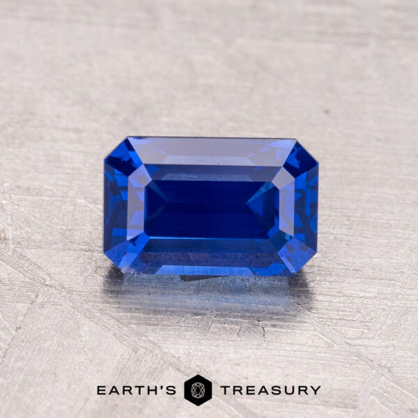 A 1.48-carat Ceylon sapphire (heated) in a rectangular shape on a textured gray background with "Earth's Treasury" at the bottom.