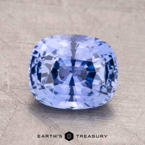 A 2.66-carat Ceylon sapphire, cushion-cut and blue, is displayed on a textured metallic surface with the "Earth's Treasury" logo visible at the bottom.