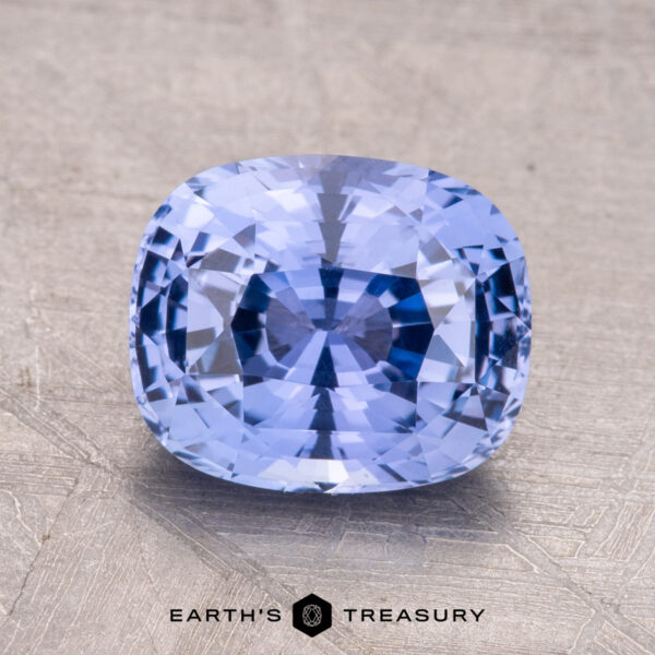 2.66-Carat Ceylon Sapphire A 2.66-carat Ceylon sapphire, cushion-cut and blue, is displayed on a textured metallic surface with the "Earth's Treasury" logo visible at the bottom.