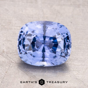 A 2.66-carat Ceylon sapphire, cushion-cut and blue, is displayed on a textured metallic surface with the "Earth's Treasury" logo visible at the bottom.