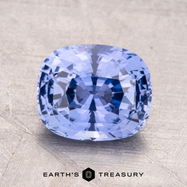 A 2.66-carat Ceylon sapphire, cushion-cut and blue, is displayed on a textured metallic surface with the "Earth's Treasury" logo visible at the bottom.
