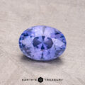 An oval-cut, faceted Ceylon Sapphire (1.32 carats) lies on a textured surface with the "Earth's Treasury" logo below.