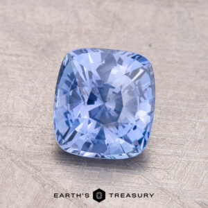 A 1.60-carat Ceylon blue sapphire, cushion-cut, is displayed on a textured surface with the "Earth's Treasury" logo beneath.