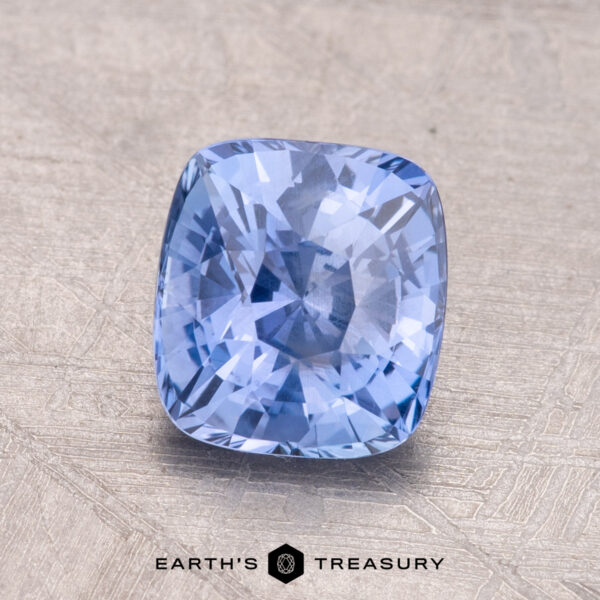 1.60-Carat Ceylon Sapphire A 1.60-carat Ceylon blue sapphire, cushion-cut, is displayed on a textured surface with the "Earth's Treasury" logo beneath.