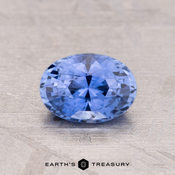 Oval-cut 1.33-Carat Ceylon Sapphire displayed on a textured surface, with "Earth's Treasury" logo below.