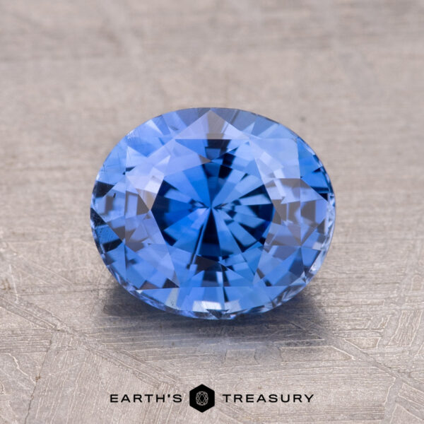 2.29-Carat Ceylon Sapphire (Heated) A 2.29-carat round brilliant-cut Ceylon sapphire (heated) rests on a textured surface, showcasing the "Earth's Treasury" logo at the bottom.