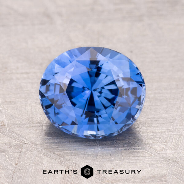 A 2.29-carat round brilliant-cut Ceylon sapphire (heated) rests on a textured surface, showcasing the "Earth's Treasury" logo at the bottom.