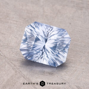 A 1.68-carat Ceylon Sapphire, a rectangular faceted blue gemstone, sits on a textured surface with the "Earth's Treasury" logo at the bottom.