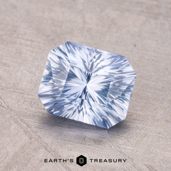 1.68-Carat Ceylon Sapphire A 1.68-carat Ceylon Sapphire, a rectangular faceted blue gemstone, sits on a textured surface with the "Earth's Treasury" logo at the bottom.