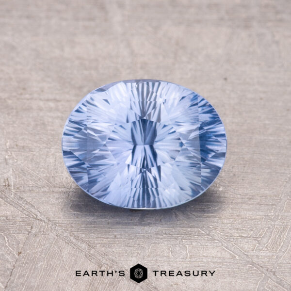 1.61-Carat Ceylon Sapphire A 1.61-carat Ceylon Sapphire, faceted and round, features a light blue hue set against a textured background.