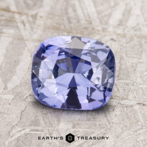 A 1.91-carat cushion-cut violet Ceylon sapphire displayed on a textured surface.