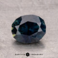 A 2.29-carat round-cut Australian sapphire in dark blue appears on a textured surface, with "Earth's Treasury" beneath it.