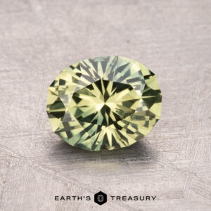 A round brilliant cut green gemstone on a textured surface, with the text "1.43-Carat Australian Sapphire (Heated)" below it.