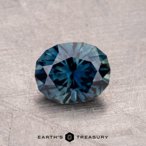 A 1.29-carat round-cut Australian sapphire (heated) displayed on a textured surface.
