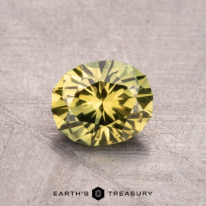 1.25-carat Australian sapphire (heated), round-cut, yellow gemstone on a textured surface.