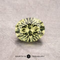 A round, faceted green gemstone measuring 1.09 carats rests on a textured surface with the "Earth's Treasury" logo below.