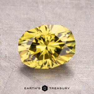 A 2.52-carat Australian Sapphire (heated) with a yellow hue is showcased on a textured gray surface, featuring the "Earth's Treasury" logo at the bottom.