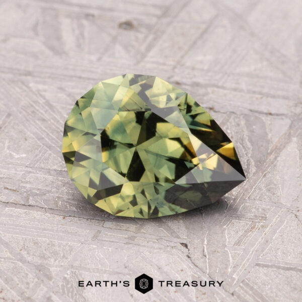 1.58-Carat Australian Sapphire (Heated) A 1.58-carat, faceted pear-shaped Australian sapphire (heated), resting on a textured gray surface.
