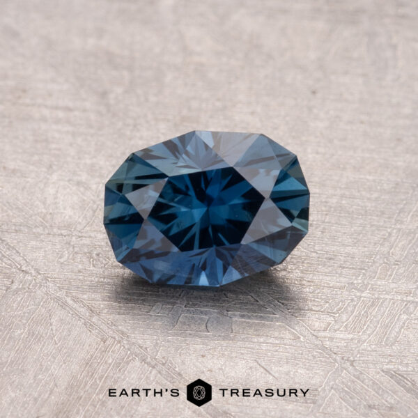 1.14-Carat Australian Sapphire (Heated) A 1.14-carat Australian sapphire (heated) rests on a textured surface, showcasing the "Earth's Treasury" logo beneath it.