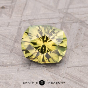 A 1.43-carat Australian sapphire (heated) sits on a textured gray stone background with a star-like pattern, showcasing Earth's Treasury branding.