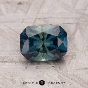 Blue-green faceted 1.40-carat Australian Sapphire with a textured surface; text reads "Earth's Treasury.