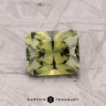 A faceted rectangular Australian Sapphire (1.62-Carat, Heated) in green rests on a textured gray surface, with the "Earth's Treasury" logo and text below.
