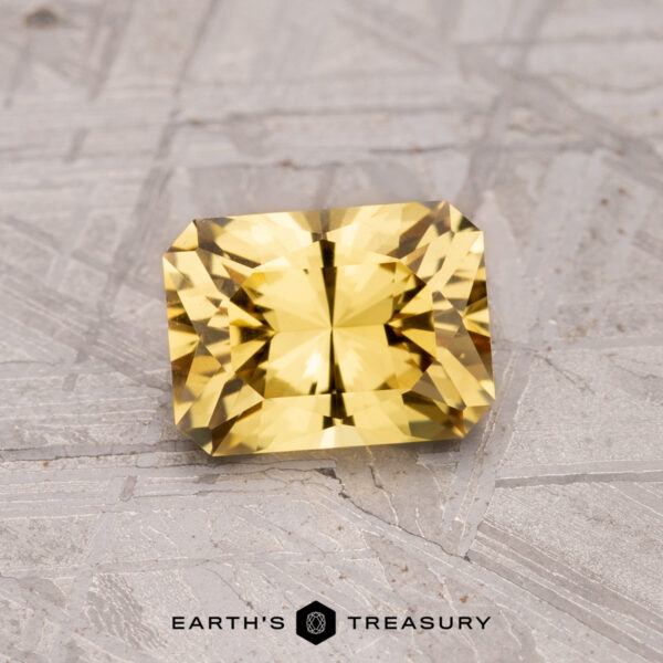 A 1.18-carat Australian sapphire with a rectangular faceted cut is displayed on a textured surface.