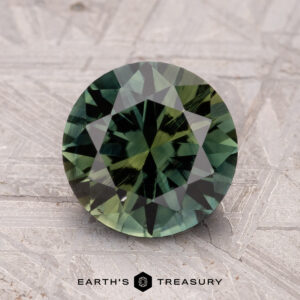 A 2.57-carat Australian sapphire (heated), with round green facets, is placed on a textured gray surface labeled "Earth's Treasury" at the bottom.