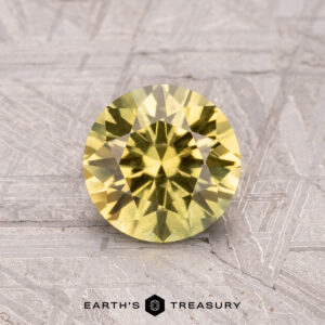 A 1.26-carat Australian sapphire (heated) sits on a textured gray surface, with the "Earth's Treasury" logo at the bottom.