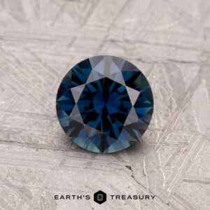 1.01-carat Australian sapphire (heated) set against a textured gray surface.