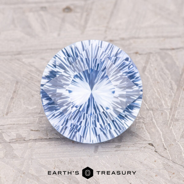 2.00-Carat Ceylon Sapphire A 2.00-carat round brilliant-cut Ceylon sapphire on a textured surface, with text below reading "EARTH'S TREASURY.