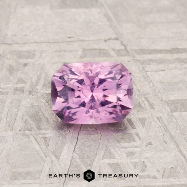 0.69-Carat Montana Sapphire A 0.69-carat Montana Sapphire with a radiant cut is displayed on a textured gray surface, featuring the "Earth's Treasury" text at the bottom.