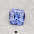 A 1.27-carat heated Ceylon sapphire with a square brilliant cut rests on a textured light gray surface. "EARTH'S TREASURY" is displayed at the bottom of the image.