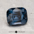 A 2.74-carat, cushion-cut deep blue spinel is displayed on a light, textured surface with the text “EARTH'S TREASURY” at the bottom.