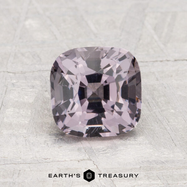1.86-Carat Spinel A 1.86-carat, cushion-cut light purple Spinel is displayed on a textured light gray surface with the "Earth’s Treasury" logo beneath.