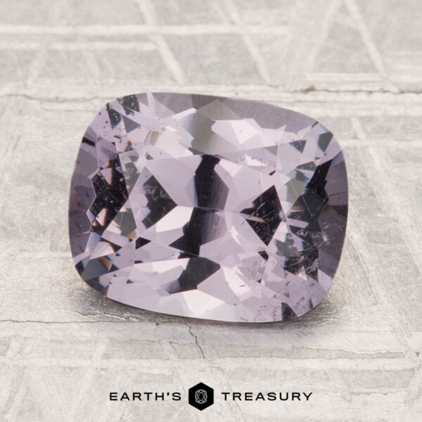 2.60-Carat Spinel A 2.60-carat, cushion-cut pale purple spinel gemstone is displayed on a textured gray surface with "Earth's Treasury" at the bottom.