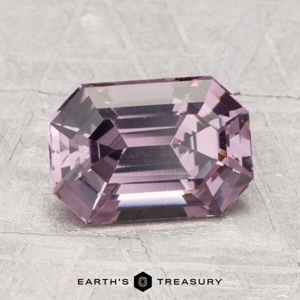 2.60-Carat Spinel A rectangular, step-cut 2.60-carat Spinel gemstone displayed on a textured gray surface, with the “Earth’s Treasury” logo and text below.