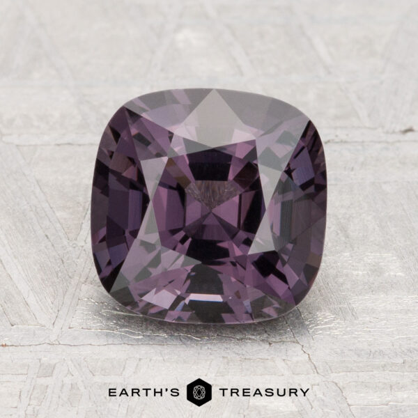 2.65-Carat Spinel A 2.65-carat cushion-cut purple spinel is displayed on a textured gray surface, with the text "EARTH'S TREASURY" at the bottom.