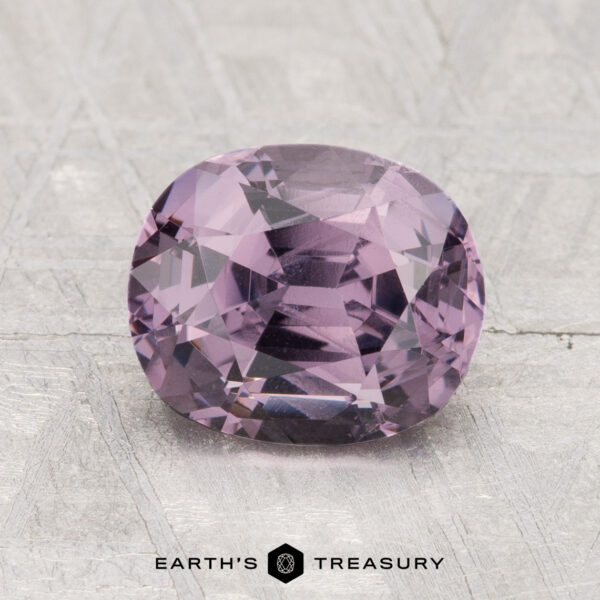 2.11-Carat Spinel A 2.11-carat cushion-cut purple spinel is shown on a textured light gray surface with "EARTH'S TREASURY" at the bottom.