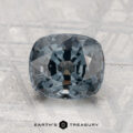 A 2.19-carat, cushion-cut dark gray spinel rests on a textured surface with "EARTH'S TREASURY" displayed beneath.
