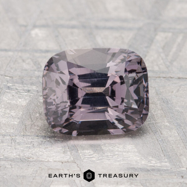 2.04-Carat Spinel A 2.04-carat, cushion-cut purple spinel is displayed on a textured gray surface with “Earth’s Treasury” at the bottom.