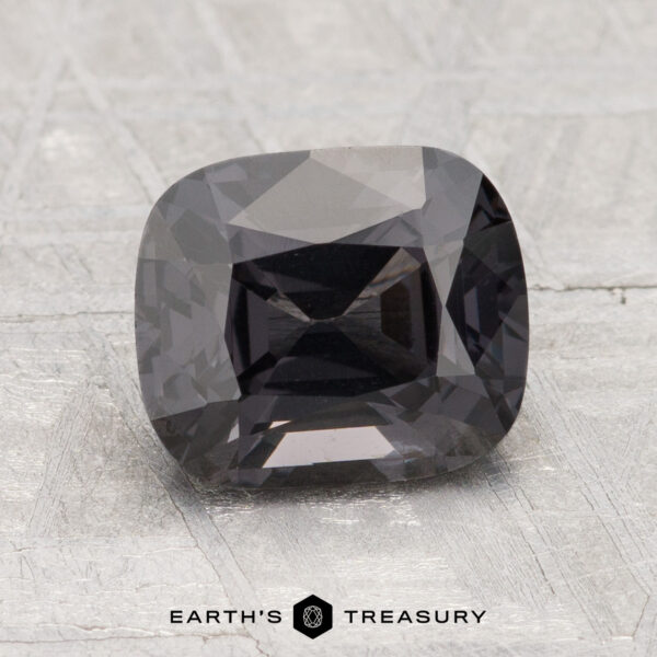 2.45-Carat Spinel A 2.45-carat cushion-cut gray spinel with a faceted surface is displayed on a textured gray background. The text "Earth's Treasury" appears at the bottom.