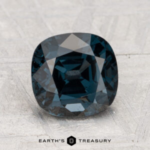 A 2.80-carat cushion-cut dark blue spinel is shown on a light gray textured surface, with the "Earth's Treasury" logo and text at the bottom.